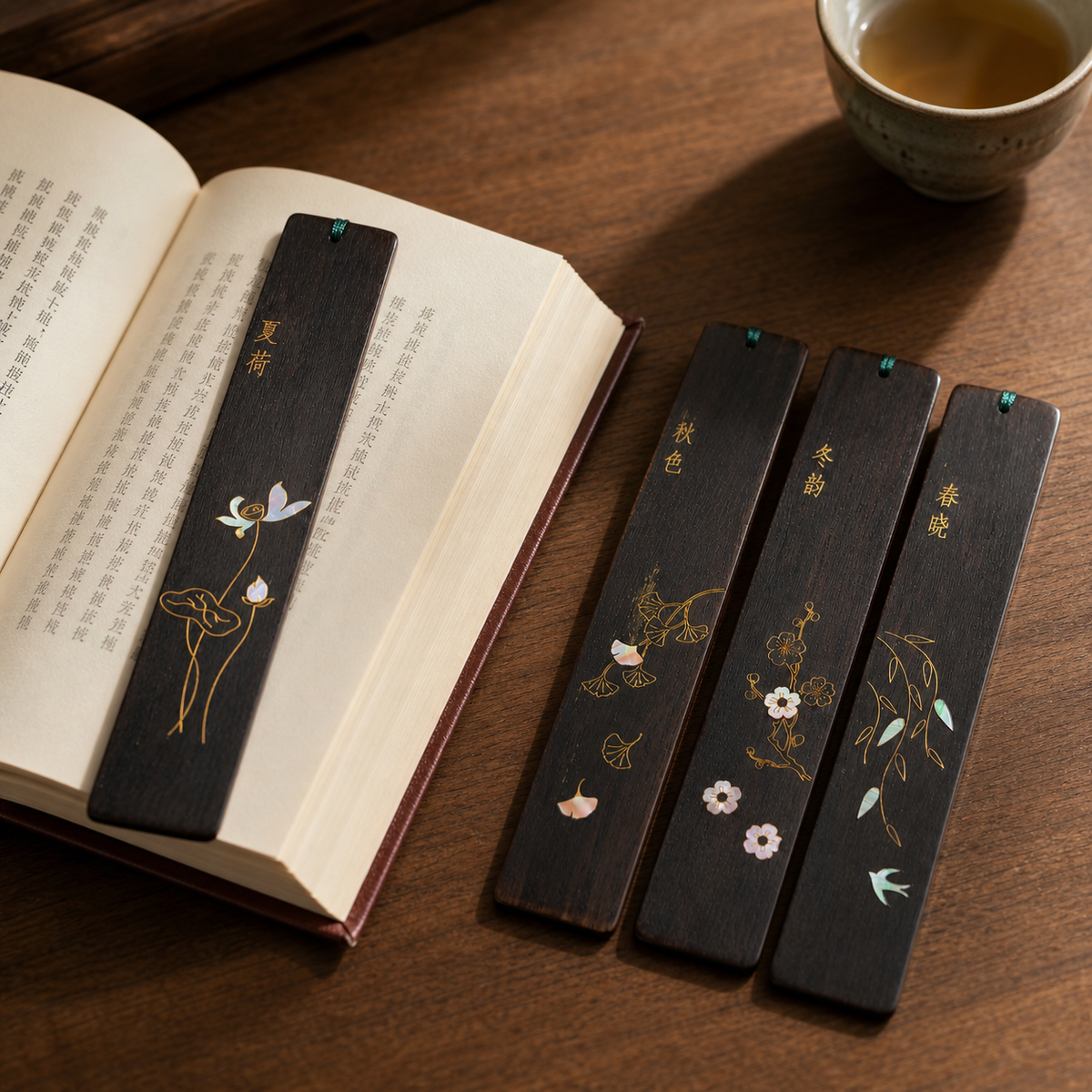 Four Seasons shell-inlay bookmarks beside an open book and tea